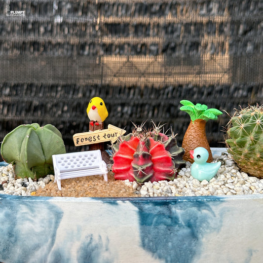 Miniature cactus garden with birds, and a palm tree in blue and white concrete planter