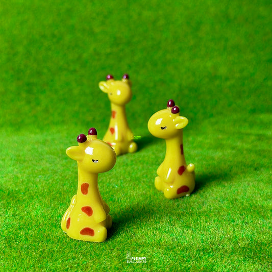Three small giraffe figurines on a green surface