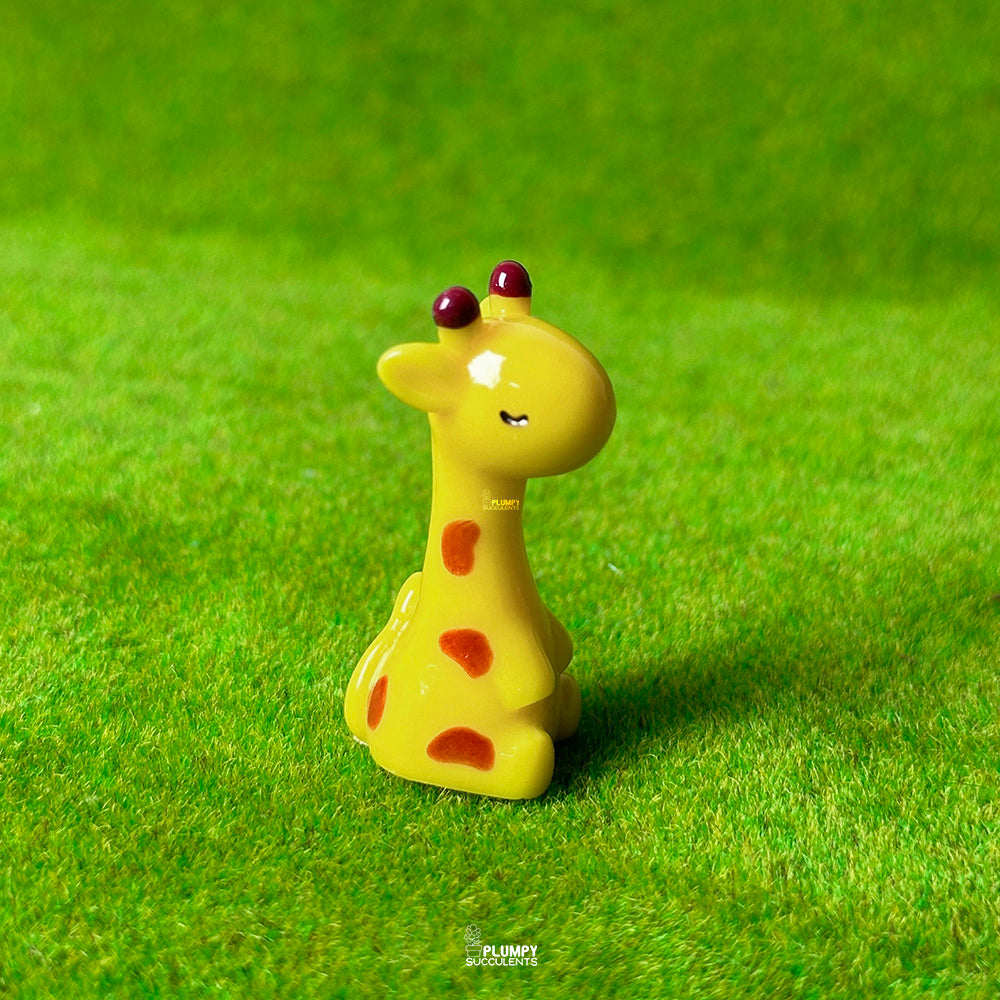 Yellow giraffe figurine with red spots on a green grass background