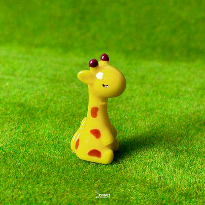 Yellow giraffe figurine with red spots on a green grass background