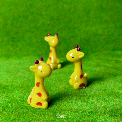 Three small giraffe figurines on a green surface